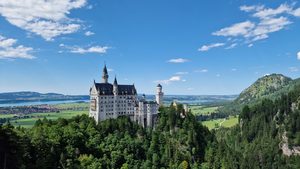Le château de Neuschwanstein émergeant de la forêt face aux montagnes bavaroises