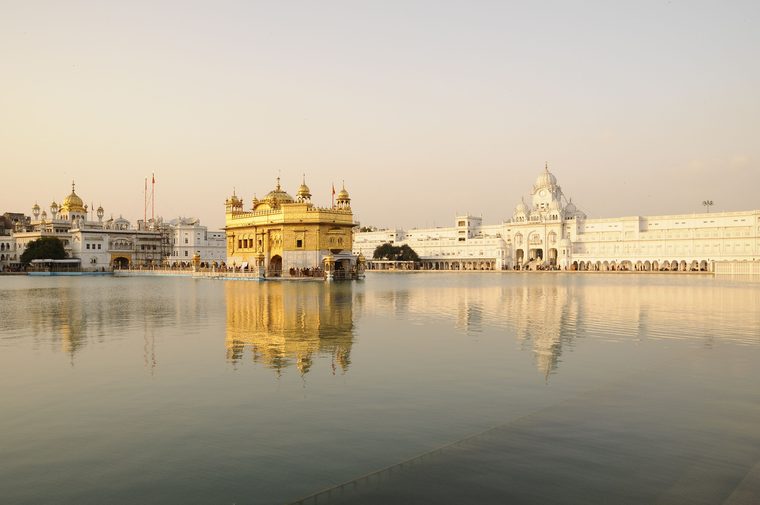 Le Temple d'Or d'Amritsar illuminé à la tombée de la nuit, se reflétant dans le bassin sacré