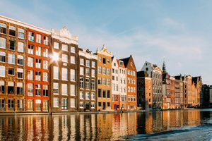Des vélos stationnés sur un pont enjambant un canal bordé de maisons traditionnelles en briques à Amsterdam