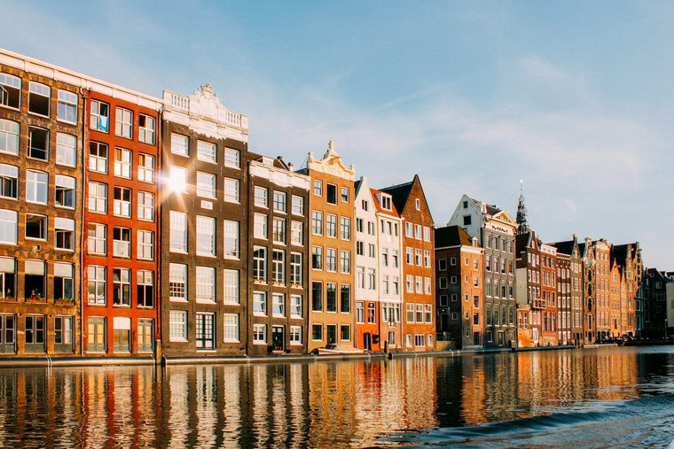 Des vélos stationnés sur un pont enjambant un canal bordé de maisons traditionnelles en briques à Amsterdam