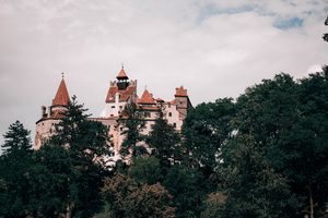 Le château de Bran perché sur son piton rocheux entouré d'arbres en Transylvanie