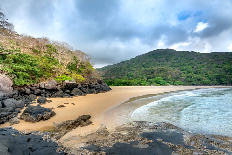 Plage de sable fin et eau turquoise bordée de jungle à Côn Đảo