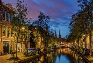 Les canaux de Delft bordés d'arbres et de vélos, avec la tour de la vieille église en fond