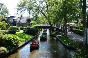 Un bateau naviguant sur un canal bordé de maisons au toit de chaume