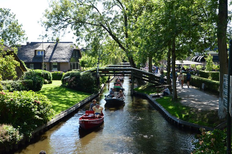 Un bateau naviguant sur un canal bordé de maisons au toit de chaume