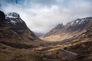 Une route sinueuse traversant la vallée de Glencoe sous un ciel nuageux