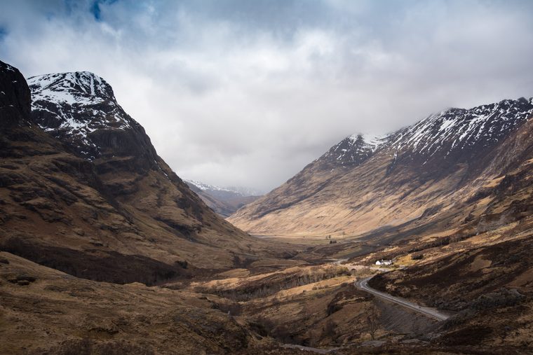 Une route sinueuse traversant la vallée de Glencoe sous un ciel nuageux