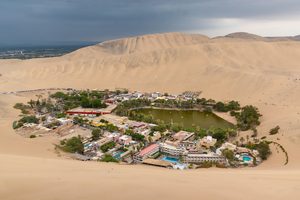 L'oasis de Huacachina entourée par les immenses dunes de sable au coucher du soleil
