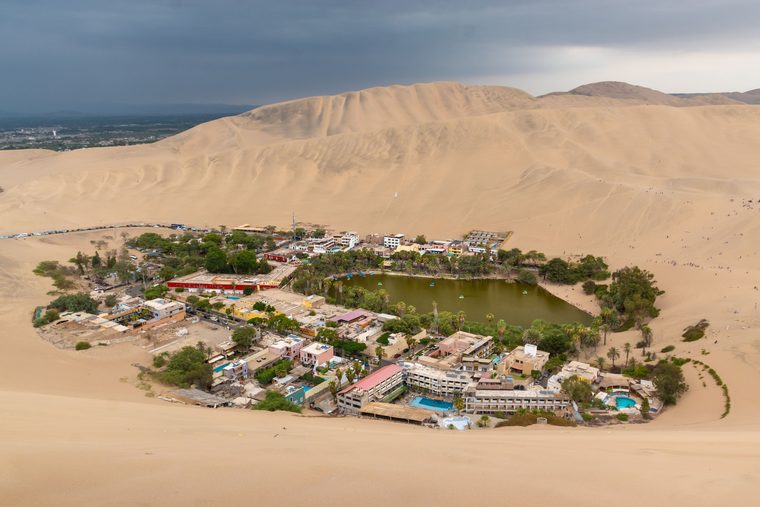 L'oasis de Huacachina entourée par les immenses dunes de sable au coucher du soleil