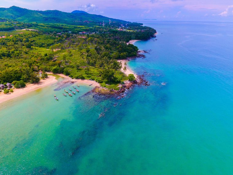 Plage de sable fin et bateaux longue queue typiques sur la côte ouest de Koh Lanta