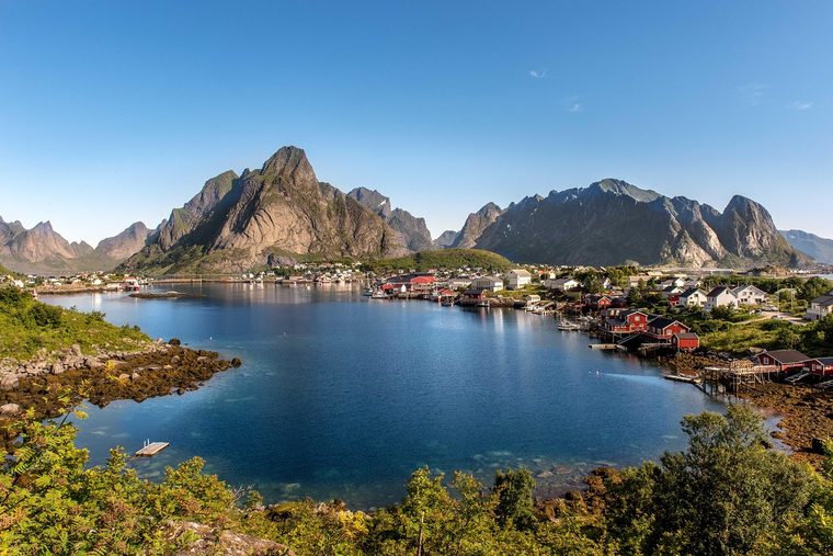 Le village de Reine avec ses rorbuer rouges au bord de l'eau et les montagnes escarpées en arrière-plan