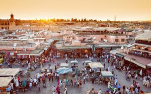 La place Jemaa el-Fna animée au coucher du soleil avec la mosquée Koutoubia en arrière-plan