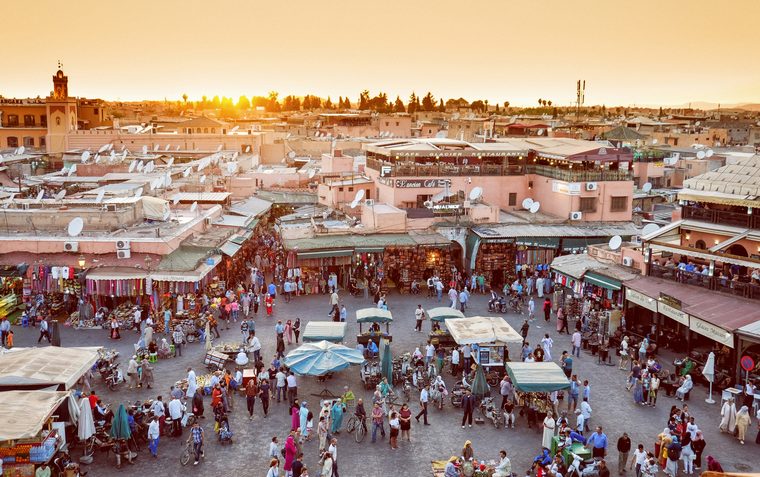 La place Jemaa el-Fna animée au coucher du soleil avec la mosquée Koutoubia en arrière-plan