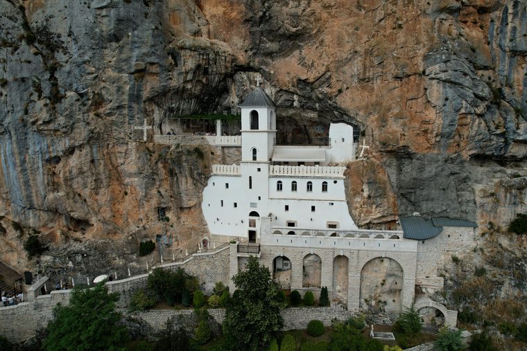 La façade blanche du monastère supérieur d'Ostrog encastrée dans la falaise