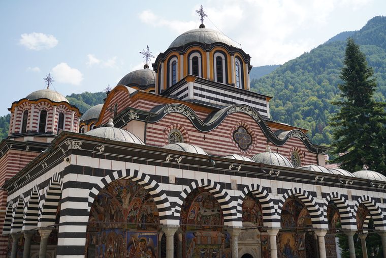 La cour intérieure du monastère de Rila et ses arcades rayées sous les montagnes