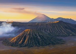 Le cratère fumant du mont Bromo entouré par la mer de sable au lever du soleil