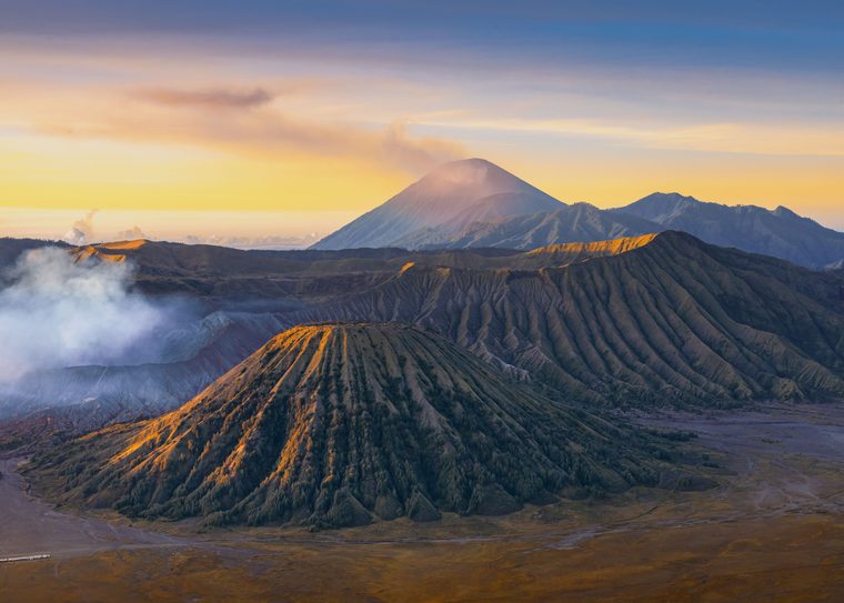 Le cratère fumant du mont Bromo entouré par la mer de sable au lever du soleil
