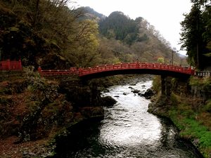 Le pont sacré Shinkyo rouge traversant la rivière entouré par la forêt à Nikko