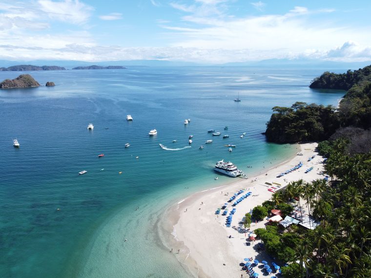 Plage de sable clair et eaux calmes bordées de végétation sur la péninsule de Papagayo