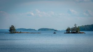Un chalet en bois rouge au bord du lac Saimaa entouré de sapins