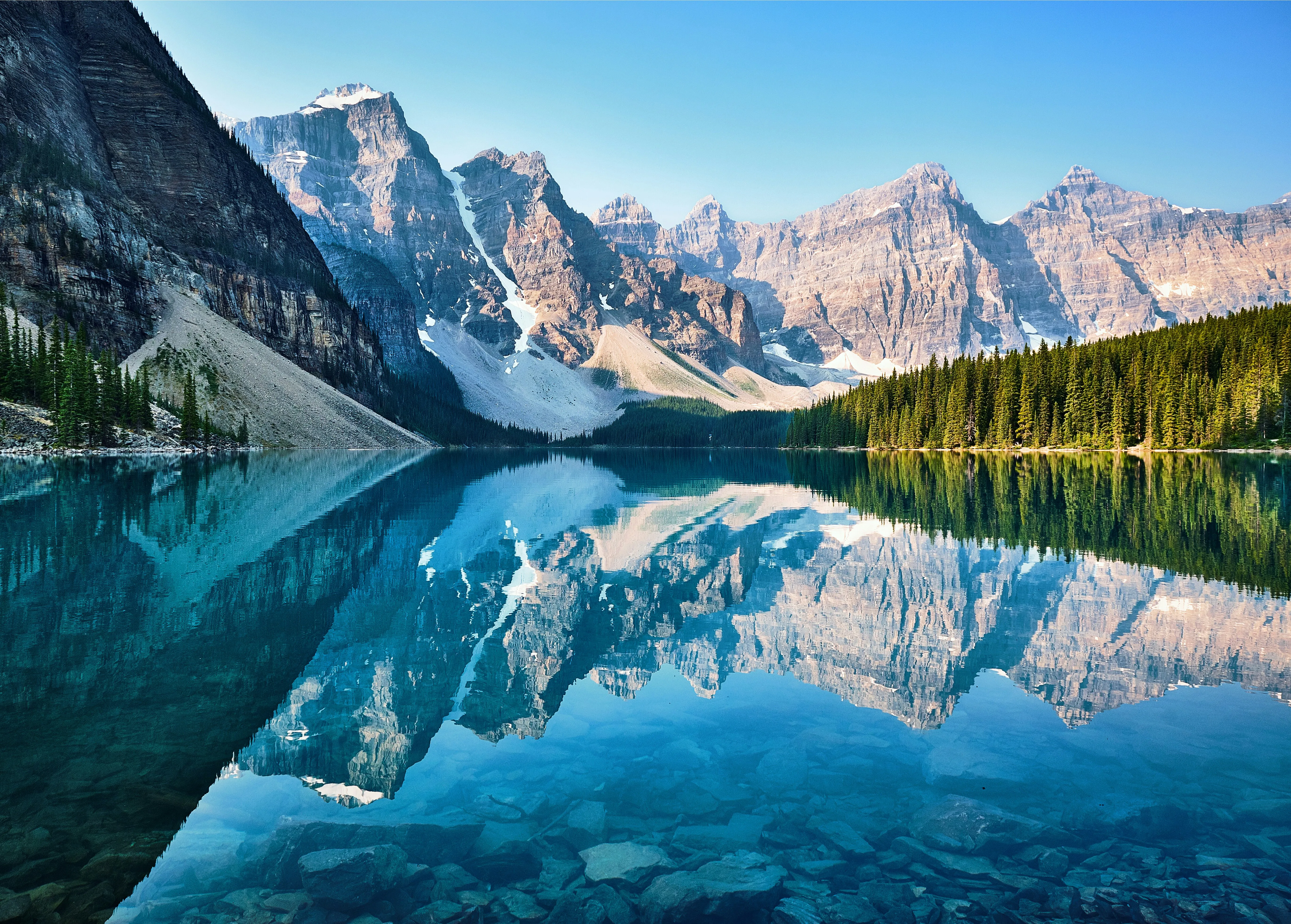 Les eaux turquoises d'un lac glaciaire entouré de forêts de conifères et de pics enneigés
